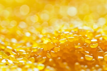 Poster - A shallow depth of field focuses on a heap of bright yellow plastic granules, with the background blurred and out of focus