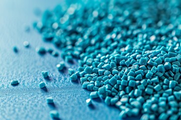 Poster - A vibrant closeup of turquoise plastic granules scattered on a smooth, blue surface. The photo captures the texture and color of the granules