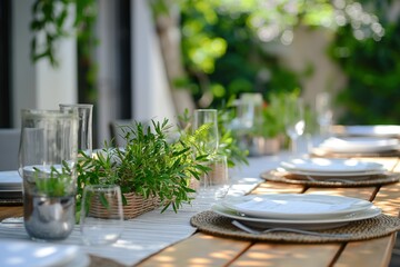 Outdoor dining scene with wooden table set for festive banquet. White plates, silverware, glasses on minimalist runner decorated with green plants. Plants surround table creating tranquil atmosphere.