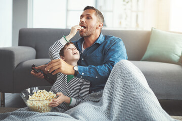 Sticker - Dad, tv remote and kid with popcorn by sofa for entertainment, snack and watching cartoon together. Family, father and son with feeding at home for care, love and streaming of show in living room