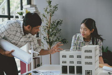 Wall Mural - two architects discussing sustainable building project, examining scale model and blueprints, brains