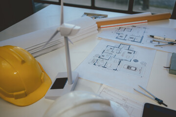 Wall Mural - scale model of a wind turbine is standing on an architect's desk amidst blueprints and drafting tool