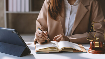 Wall Mural - Focused female lawyer takes notes in her office, surrounded by legal documents and symbols of justice, showcasing her professionalism and dedication