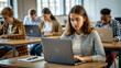© NewFresh  - Serious female student working on laptop while sitting at desk in classroom