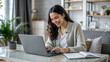 © NewFresh  - Smiling young woman working on laptop and making notes in notepad