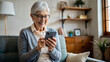 © NewFresh  - Smiling senior woman using mobile phone while sitting on sofa at home
