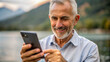 © NewFresh  - Portrait of a senior man using his mobile phone on a lake