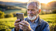 © NewFresh  - Senior man using mobile phone outdoor at sunset in the countryside. Elderly people and technology concept.