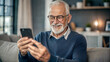 © NewFresh  - Portrait of senior man using smartphone while sitting on sofa at home