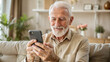 © NewFresh  - Portrait of senior man using smartphone while sitting on sofa at home