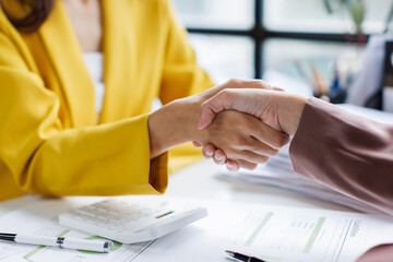 Two diverse professional business women executive leaders shaking hands at office meeting