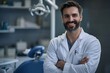 © antusher - Smiling male dentist in white coat standing at dental office