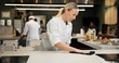 © CineLens2024/peopleimages.com - Woman, cleaning and chef wipe counter for dinner rush prep, hygiene and bacteria removal. Dust, person and employee in kitchen, cloth or restaurant with sanitation, disinfection or hospitality policy