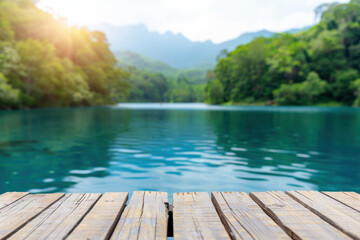 Poster - Serene lake landscape with clear water, wooden pier, lush green trees, and distant mountains under a bright sky. Perfect for nature and travel themes.