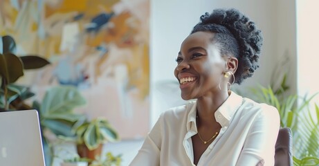 Poster - Smiling woman sitting at desk with laptop in office, laughing and looking away while working on computer . Businesswoman smiling during meeting or brainstorming session near canvas painting. Realistic