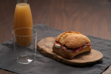 Wall Mural - Sandwich with bresaola, mozzarella and pest on olive board with orange juice