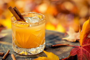 Vanilla cinnamon maple whiskey sour cocktail , autumn leaves on background