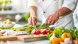 © Pual GotoMars - A chef preparing fresh vegetable salad in a bright kitchen. The chef slices tomatoes along with other fresh ingredients on a wooden cutting board.