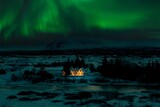 Beautiful winter night landscape with the Northern Lights over a small illuminated house in Iceland