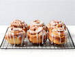 © TatjanaMeininger - Close up of fresh baked delicious cinnamon rolls with sugar glaze on top on baking rack, blurry background