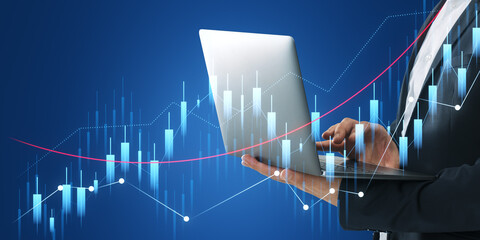Poster - A person in a business suit holding a laptop, with futuristic financial graph holograms overlaid, on a dark blue background, depicting the concept of financial analysis