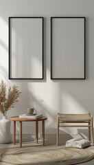 Aufkleber - A minimalist setting with two blank frames on a white wall, a small table with books and a cup, and a woven chair