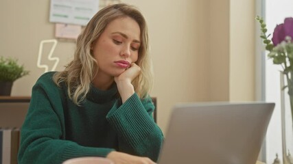 Sticker - A tired young woman working on her laptop in the living room of her apartment, portraying a sense of fatigue and concentration.