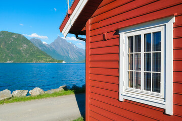 Wall Mural - Traditional Scandinavian houses with moss on the roof. Beautiful mountain lake in Norway. Nature in the fjords. Vacation and travel in summer Norway.