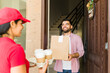© AntonioDiaz - Attractive latin man receiving his take away food order from a delivery woman at his front door