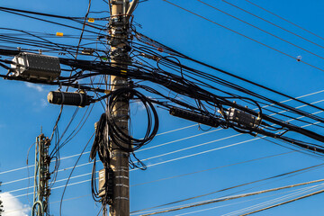 Many wires attached to the electric pole, the chaos of cables and wires on an electric pole, blue sky background, technological combination concept in Brazil