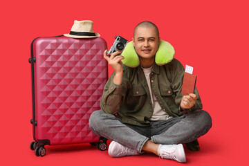 Sticker - Young male tourist with photo camera, passport and suitcase on red background