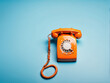 © Nyetock - Busy retro phone orange color, handset receiver on blue background. copy space.