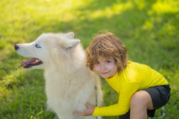 Wall Mural - Child and dog outdoor portrait. Kid hugging dog in the summer park. Kid hugs a dog in the park. Pets and Childhood. Kids Life style with dogs. Pet care. Kid plays with a husky dog on green field.