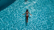 © Christian Müller - drone view of a woman swimming in a swimming pool