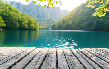 Poster - Serene lakeside view from a wooden dock with lush green forest and mountains in the background on a sunny day, perfect for nature and outdoor enthusiasts.