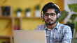 © Jack - Indian young man wearing a headset conducts a webinar, online conference sitting at a laptop in the office
