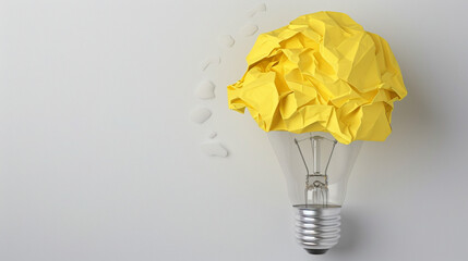 Yellow crumpled paper ball and drawn lamp bulb