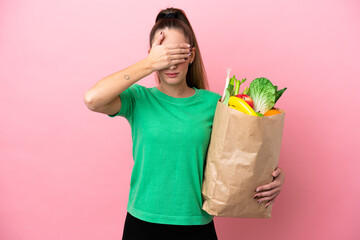 Young woman holding a grocery shopping bag covering eyes by hands. Do not want to see something