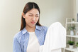 © Pormezz - housewife smelling bad odor from damp clothes during laundry.