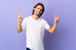 © luismolinero - Young handsome man isolated on purple background showing victory sign with both hands