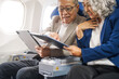 © NanSan - A mature couple enjoys a plane ride, seated near the window. They gaze out at the sky, savoring the view and the excitement of travel, creating cherished memories together.