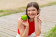 © luismolinero - Young pretty woman at outdoors holding an apple with happy expression