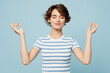 © ViDi Studio - Young woman she wears striped t-shirt casual clothes hold spreading hands in yoga om aum gesture relax meditate try to calm down isolated on plain pastel light blue cyan background. Lifestyle concept.