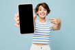 © ViDi Studio - Young woman wear striped t-shirt casual clothes hold in hand use mobile cell phone point index finger on close up blank screen area isolated on plain pastel light blue background. Lifestyle concept.