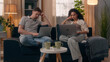 © Yuliia - Multiracial couple gadgets addict family computers technology addicted Caucasian man guy male using laptop Hispanic woman girl female typing pc working distant freelance at home couch laptops busy