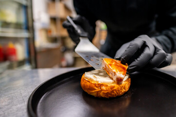 Wall Mural - Close-up of hands spreading cream on a halved bagel with a metal spatula