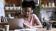 © Karen - A young woman with headphones, focused on studying with a laptop in a cozy home environment.
