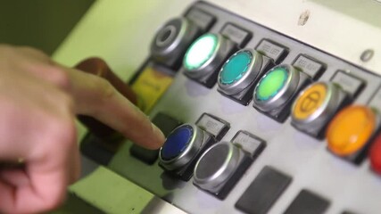 Human hand pressing start on control panel at factory. Worker managing machine pushing buttons. Engineer controlling production process on machine on control panel. Control panel in a factory close up
