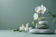 © Janjira - Elegant white orchid flowers and stacked smooth stones with lit candles, creating a serene and calming spa atmosphere on a soft green background.