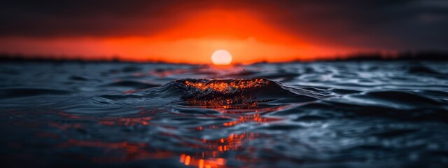  A large body of water with a bright orange sun hovering over its midpoint and a small island nestled in the water's heart